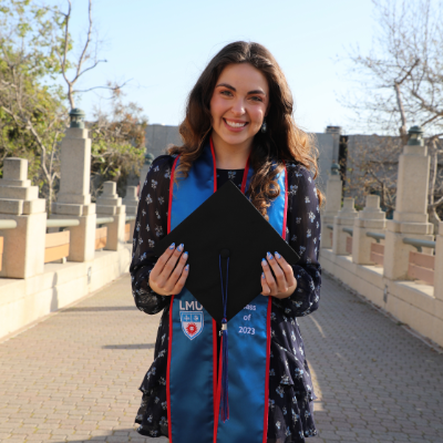 Roxy Lindy holding cap on university hall bridge